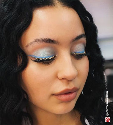 Woman wearing a chain across the lash line on blue eyeshadow