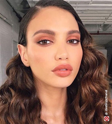 Model wearing peach eyeshadow and lipstick
