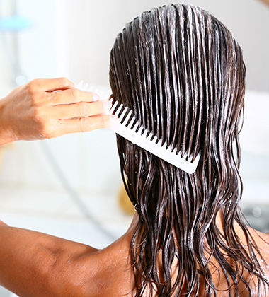 Woman applying hair conditioner with a comb