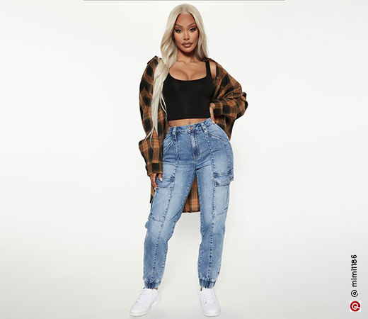 Woman wearing denim joggers with black crop top and a plaid overshirt