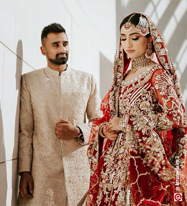 groom wearing cream coloured sherwani while the bride wears red